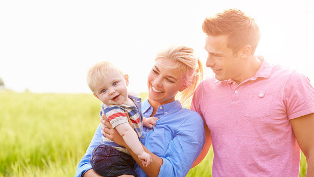 Una familia de tres juntos, los padres miran al ninÌƒo, muy felices