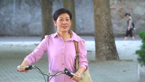 一个中年妇女推着车子看向前方